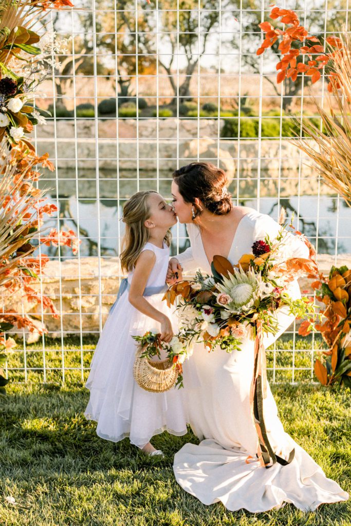 Bride sharing a tender moment with her flower girl in front of her Modern Ceremony Design