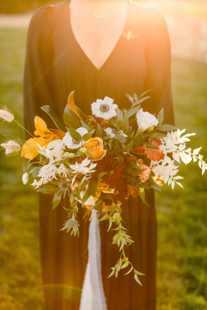 Golden sunset flare behind bridesmaid holding Edgy Modern Bouquet