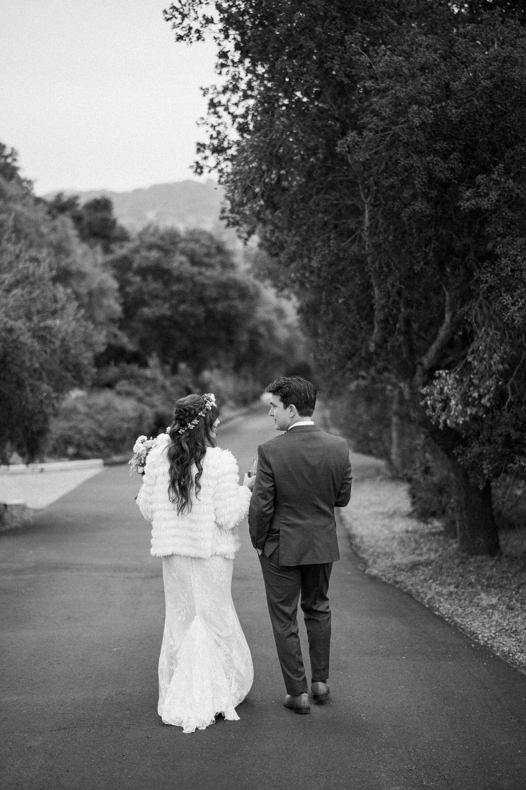 Bride and groom walking in black and white at unique 70s vibe colorful tangerine wedding at Casitas Estate by the best san luis obispo wedding planner Janet Tacy of Tacy and co.